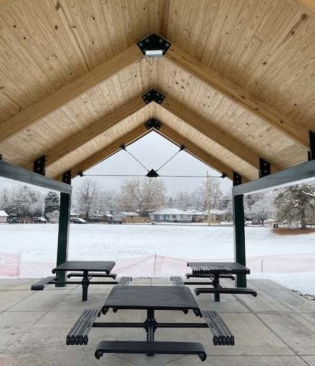 Picture of tables and wood paneled roof of new pavilion at Bates Logan Park.